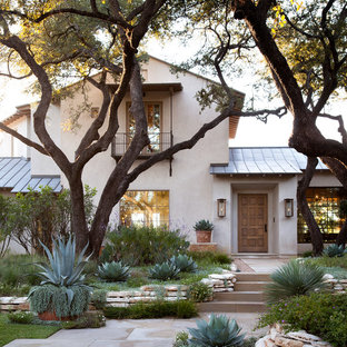 Beige mediterranean two floor house exterior in Austin with a pitched roof.
