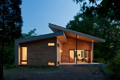 Esempio della facciata di una casa piccola marrone contemporanea a un piano con rivestimento in legno e copertura in metallo o lamiera
