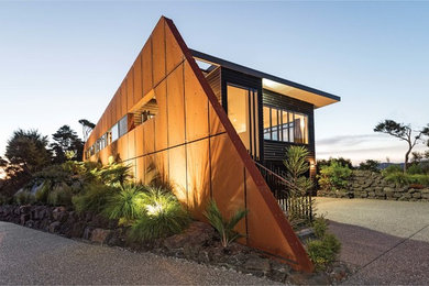 This is an example of a medium sized and black contemporary two floor detached house in Other with metal cladding, a flat roof and a metal roof.