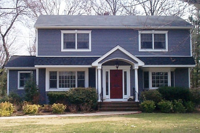 Exemple d'une grande façade de maison bleue chic en panneau de béton fibré à un étage avec un toit à deux pans et un toit en tuile.