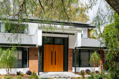 Modelo de fachada de casa blanca contemporánea de tamaño medio de dos plantas con revestimientos combinados y tejado de teja de barro