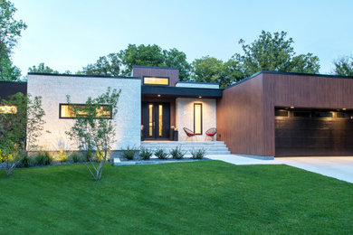 Medium sized and brown contemporary bungalow house exterior in Other with wood cladding and a flat roof.