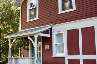 Example of a mid-sized red two-story wood gable roof design in Burlington