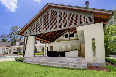 Imagen de fachada de casa beige contemporánea de una planta con revestimiento de estuco, tejado a dos aguas y tejado de teja de madera