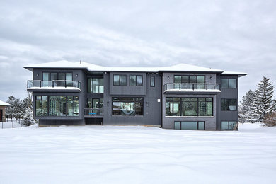 Immagine della villa grande grigia moderna a due piani con rivestimenti misti, tetto a padiglione e copertura a scandole