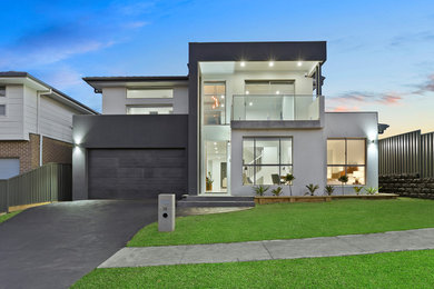 Cette photo montre une grande façade de maison grise moderne en béton à un étage avec un toit plat et un toit en métal.
