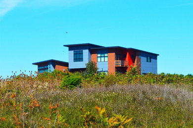 Imagen de fachada de casa roja contemporánea de tamaño medio de dos plantas con revestimientos combinados, tejado de un solo tendido y tejado de metal