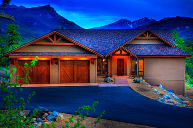 Large mountain style brown two-story stucco exterior home photo in Denver with a shingle roof