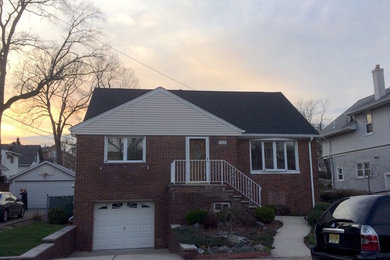 Example of a brick exterior home design in New York with a shingle roof
