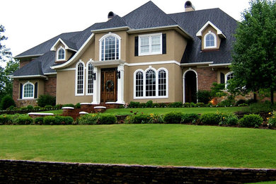 Modelo de fachada de casa beige clásica de tamaño medio de dos plantas con revestimientos combinados, tejado a cuatro aguas y tejado de teja de madera