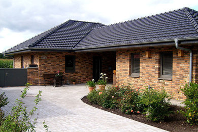 Photo of a medium sized and brown classic bungalow brick detached house in Other with a hip roof and a tiled roof.