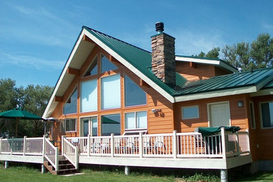 Ejemplo de fachada de casa marrón de estilo americano grande de una planta con revestimiento de madera, tejado a dos aguas y tejado de metal