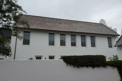 Ejemplo de fachada de casa blanca campestre de tamaño medio de dos plantas con revestimiento de estuco, tejado a dos aguas y tejado de teja de madera