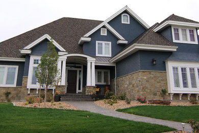 Imagen de fachada de casa azul rural grande de dos plantas con revestimientos combinados, tejado a cuatro aguas y tejado de teja de madera