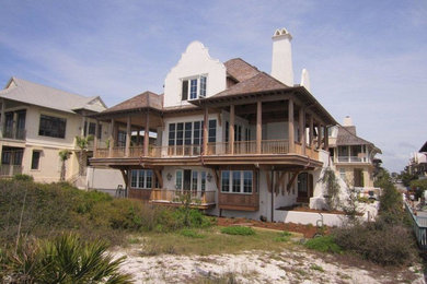 Large beach style white three-story stucco exterior home photo in Miami with a hip roof