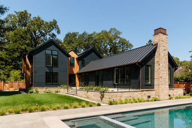 Ejemplo de fachada de casa negra de estilo de casa de campo grande de dos plantas con revestimientos combinados, tejado a dos aguas y tejado de metal