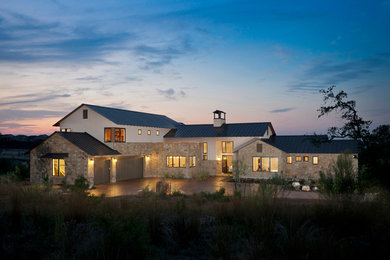 Inspiration for a large contemporary beige three-story stone exterior home remodel in Austin with a metal roof