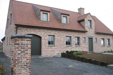 Exemple d'une grande façade de maison nature en brique avec un toit en tuile.