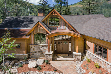 Inspiration for a large rustic brown one-story wood house exterior remodel in Albuquerque with a mixed material roof