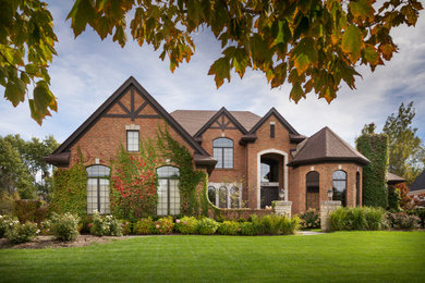 Large elegant brown two-story brick exterior home photo in Detroit with a shingle roof