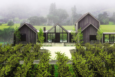 Aménagement d'une grande façade de maison multicolore moderne en bois à un étage avec un toit à deux pans et un toit en métal.