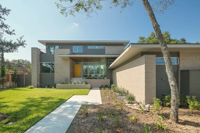 Example of a mid-sized mid-century modern gray two-story brick exterior home design in Houston
