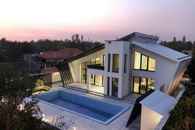 Imagen de fachada de casa blanca minimalista de tamaño medio de dos plantas con revestimiento de hormigón y tejado de metal