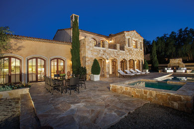 Example of a large farmhouse two-story stone exterior home design in Orange County