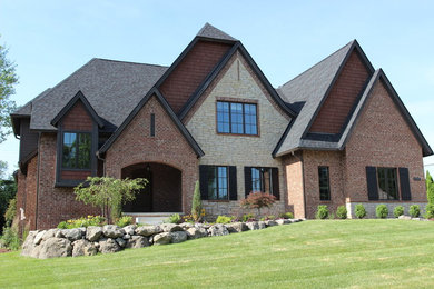 Modelo de fachada de casa gris tradicional de tamaño medio de tres plantas con revestimientos combinados, tejado a cuatro aguas y tejado de teja de madera