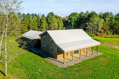 Ejemplo de fachada de casa marrón de estilo de casa de campo de tamaño medio de dos plantas con revestimiento de madera y tejado de metal