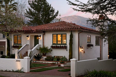 Imagen de fachada de casa blanca y roja mediterránea de tamaño medio de dos plantas con revestimiento de estuco, tejado a cuatro aguas y tejado de teja de barro