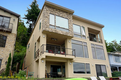 Ejemplo de fachada de casa marrón minimalista grande de tres plantas con revestimiento de estuco y tejado plano