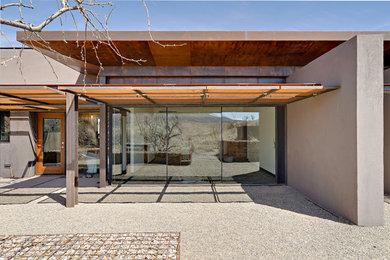 Imagen de fachada de casa marrón actual de una planta con revestimiento de hormigón y tejado plano