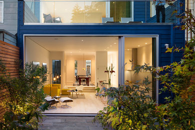 Aménagement d'une façade de maison bleue contemporaine en bois à deux étages et plus et de taille moyenne avec un toit plat et un toit mixte.