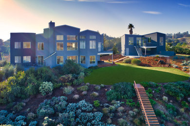 Immagine della villa grande blu moderna a due piani con rivestimenti misti, tetto piano e copertura mista