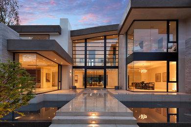 This is an example of a beige contemporary two floor glass house exterior in Los Angeles.