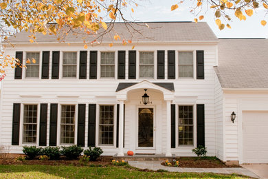 Imagen de fachada de casa blanca clásica de tamaño medio de dos plantas con revestimiento de vinilo, tejado a dos aguas y tejado de teja de madera