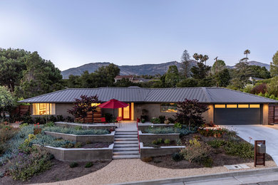 Mid-sized trendy brown one-story stucco house exterior photo in Santa Barbara with a hip roof and a metal roof