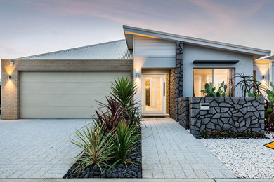 Réalisation d'une grande façade de maison grise minimaliste en brique de plain-pied avec un toit en appentis.
