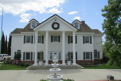 Idée de décoration pour une grande façade de maison blanche tradition en panneau de béton fibré à un étage avec un toit à deux pans.