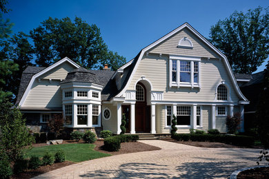 Ejemplo de fachada de casa beige clásica grande de dos plantas con revestimiento de madera, tejado a doble faldón y tejado de teja de madera