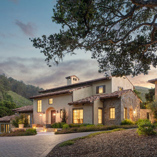 Large mediterranean beige two-story stucco exterior home idea in Orange County with a tile roof