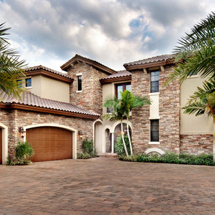 Large mediterranean beige two-story mixed siding exterior home idea in Miami with a hip roof