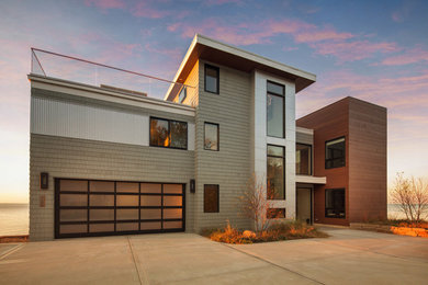 Modelo de fachada de casa gris contemporánea grande de tres plantas con revestimientos combinados y tejado plano