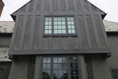 Ejemplo de fachada de casa gris de estilo americano grande de dos plantas con revestimiento de estuco, tejado a dos aguas y tejado de teja de madera