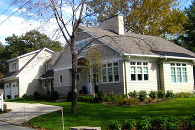 Cette photo montre une grande façade de maison beige chic en bois à un étage avec un toit à deux pans.
