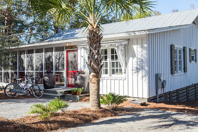 This is an example of a white beach style bungalow house exterior in Miami with wood cladding.