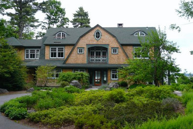 Imagen de fachada marrón clásica grande de dos plantas con revestimiento de madera y tejado a doble faldón