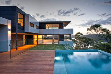 Mittelgroßes, Zweistöckiges Modernes Einfamilienhaus mit grauer Fassadenfarbe, Flachdach und Schindeldach in Sydney