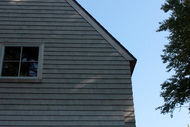 Small and beige rural two floor house exterior in Portland Maine with wood cladding and a pitched roof.